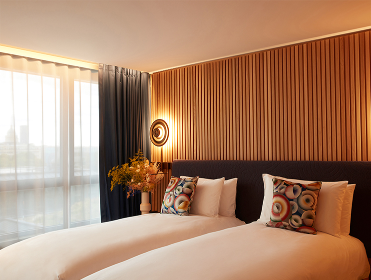 King sized bed and blue armchair with curtained windows