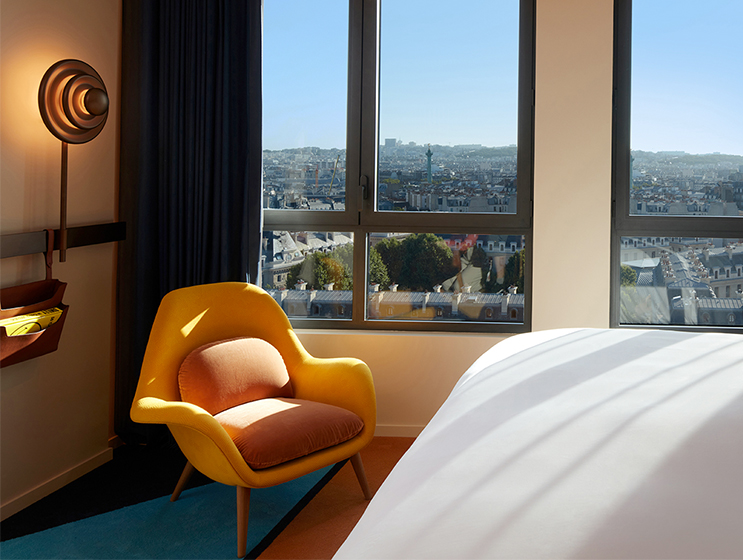 Yellow armchair next to large window overlooking the Paris Skyline