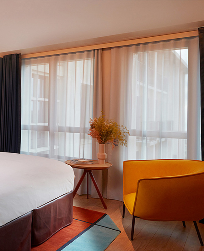 Yellow armchair and wooden side table next to curtained window