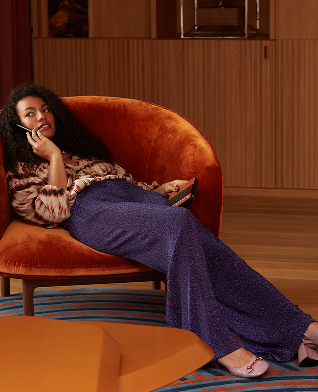 Woman on the phone sitting on burnt orange armchair