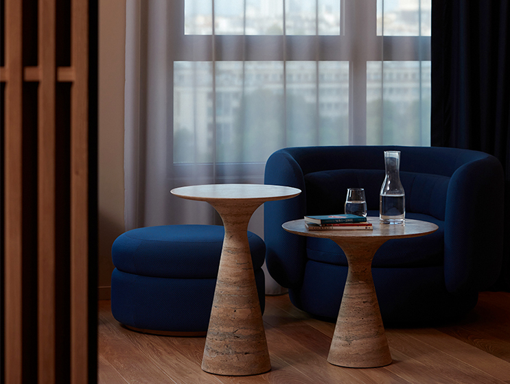 Blue Armchair and footrest behind two marble coffee tables