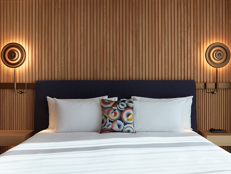 King bed with blue headboard with two mounted bedside lamps