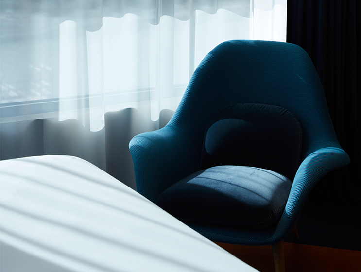Blue armchair by curtained window