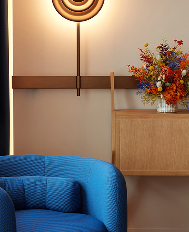Blue armchait in front of a wall mounted light and side table