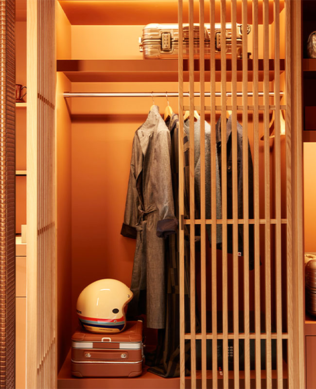 Small wardrobe with slatted wooden doors filled with jackets, bikers' helmet, suitcases and shoes