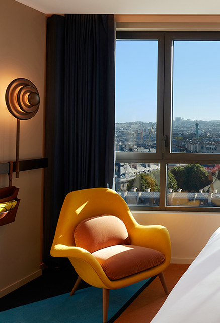 http://Yellow%20armchair%20next%20to%20large%20window%20overlooking%20the%20Paris%20Skyline