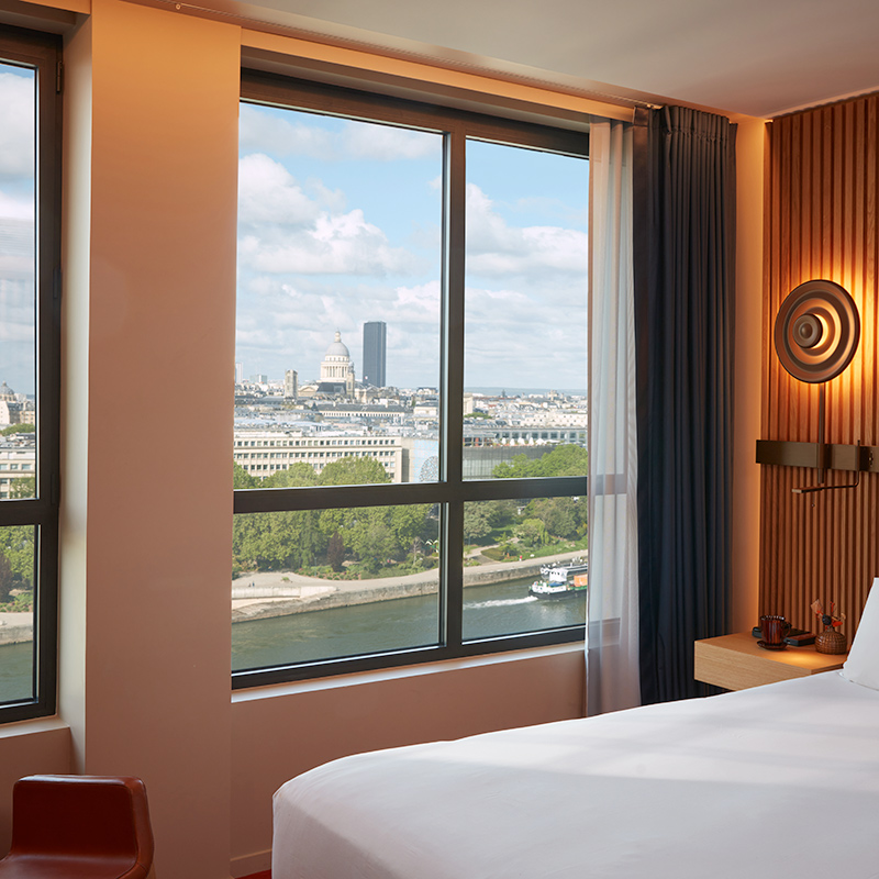 Paris skyline visible through bedroom window.