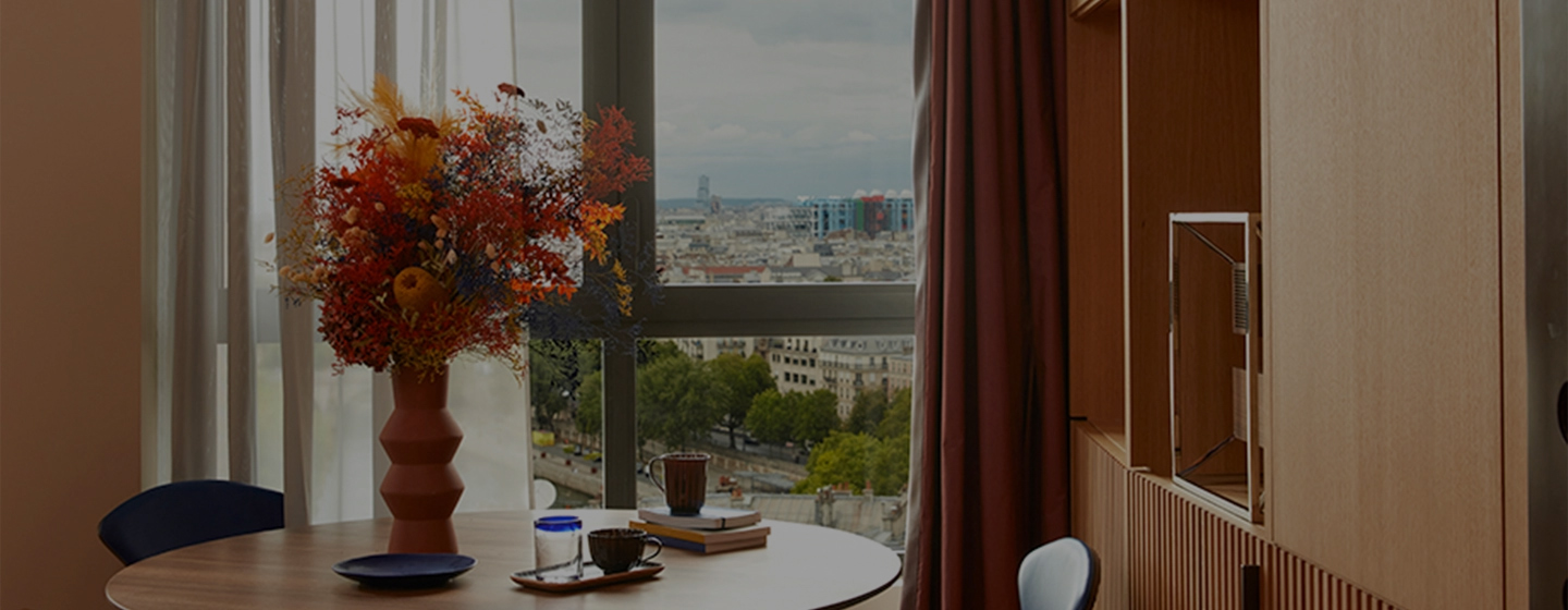 Small, circular dining table with a large window overlooking Paris