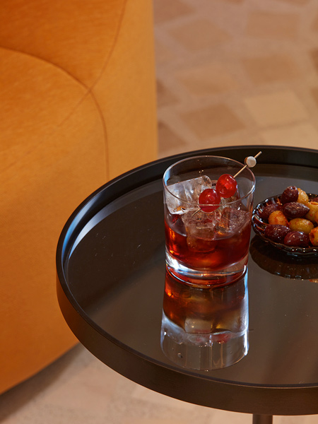 cocktail and bowl of olives on metal table