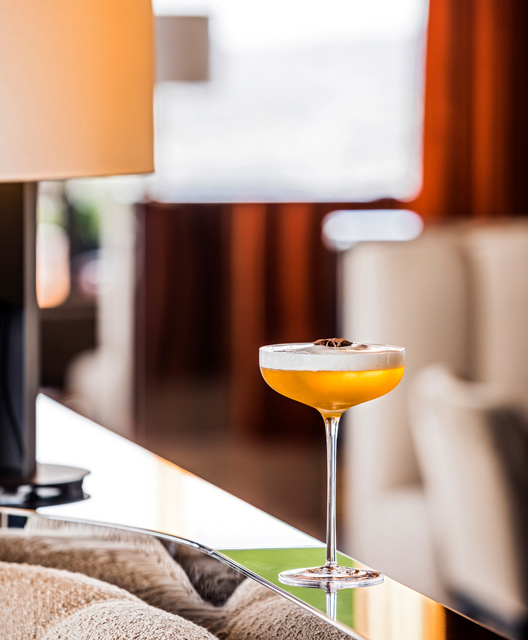 A cocktail stands on the metal edge of a couch