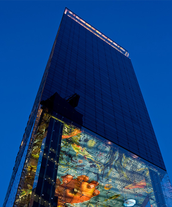 A low angle view looking up at a tall hotel building reflecting the deep blue of the sky