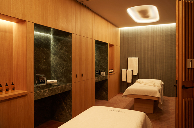 http://Two%20massage%20beds%20in%20a%20treatment%20room%20with%20wooden%20walls%20and%20marbled%20sinks.