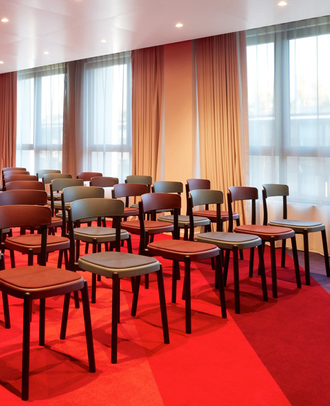 A meeting room with multiple chairs facing forward next to a long window