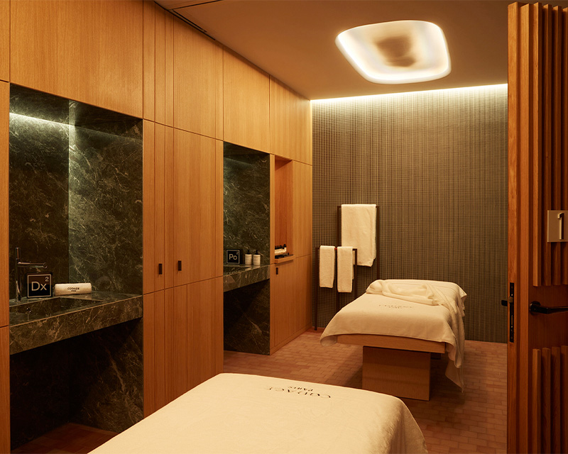 http://Two%20massage%20beds%20in%20a%20treatment%20room%20with%20wooden%20walls%20and%20marbled%20sinks.%20