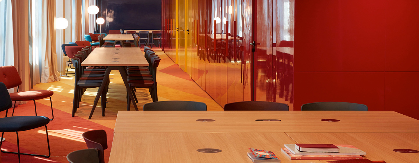 A long, autumnal coloured meeting room with 4 big meeting tables