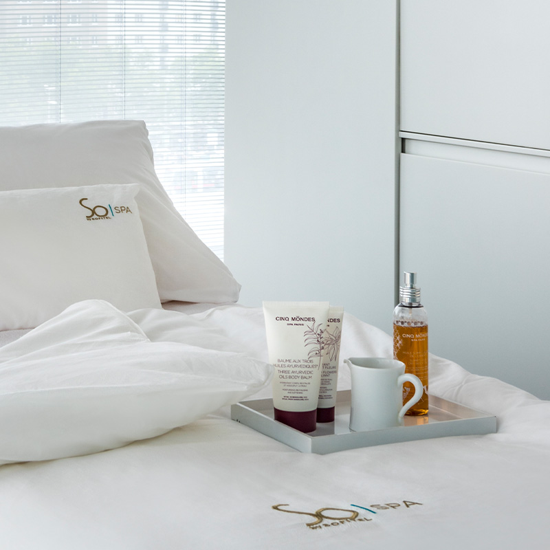 A white massage bed with a tray of various wellness treatments