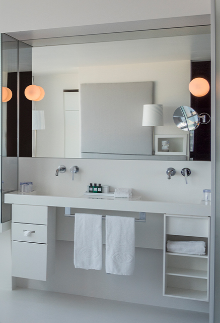 http://A%20white%20double%20sink%20vanity%20fitted%20with%20a%20large%20mirror,%20shelving%20units%20and%20make-up%20mirror
