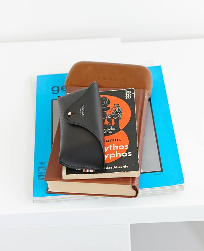 Books and a glasses case lay on a white counter top