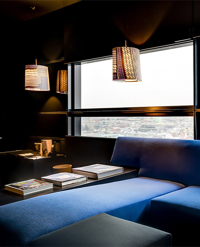 Large blue corner couch next to a large window overlooking the Viennese skyline