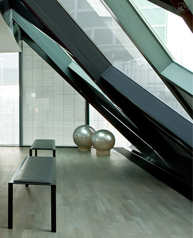 Two silver exercise balls and two resting benches in a grey fitness studio with a large slanted window