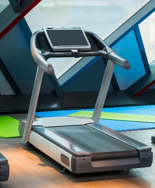 http://A%20grey%20treadmill%20with%20various%20exercise%20mats%20on%20the%20floor%20beside%20it