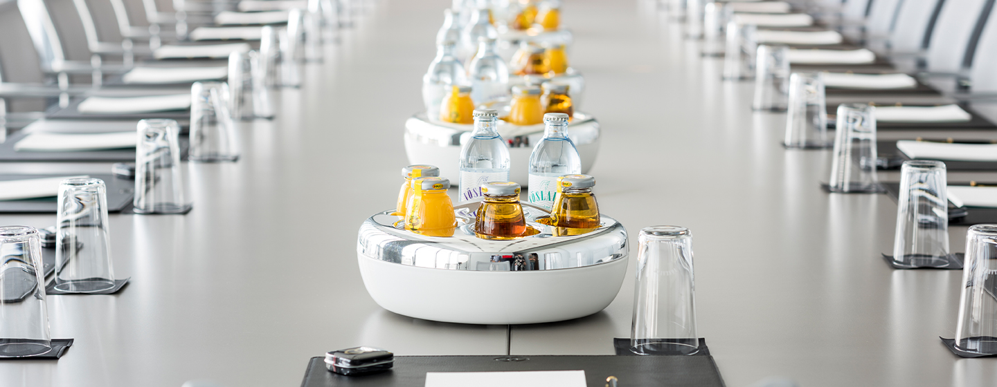 A row of beverages in bowls on a long meeting table
