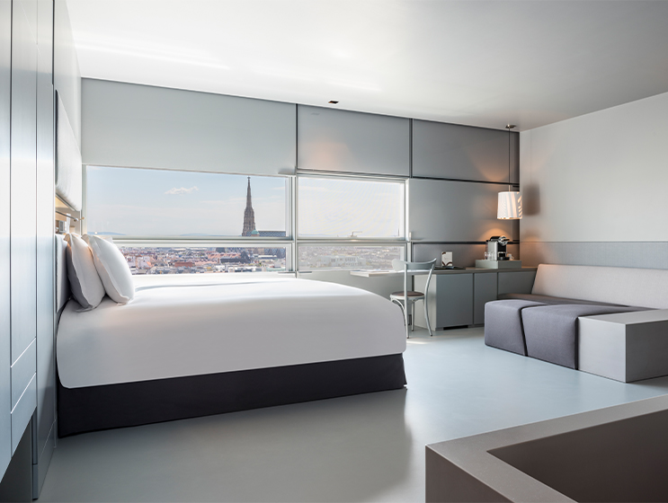 Hotelzimmer mit Doppelbett, lichtdurchflutet und mit Blick auf die Wiener Skyline