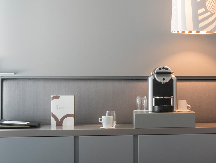 Ein Tisch mit Nespresso-Kaffeemaschine, Gläsern, weißen Tassen und der Speisekarte des SO/ Vienna