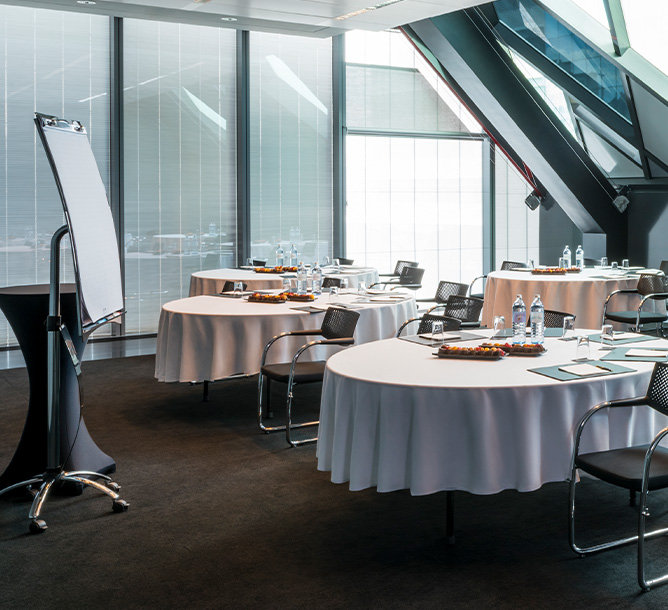 A meeting room with tables and chairs in a cabaret set-up face a flipchart