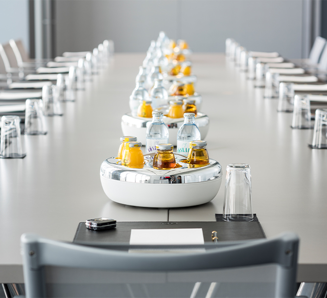 A row of beverages in bowls on a long meeting table
