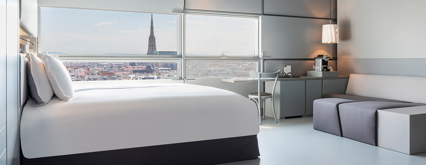 Hotel Room with Double bed filled with natural light with a view over Viennese skyline 