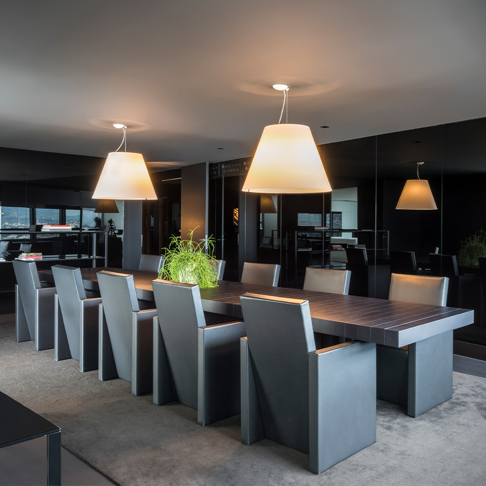 A large dining table fitting 10 peaple in a dark black and grey dining area