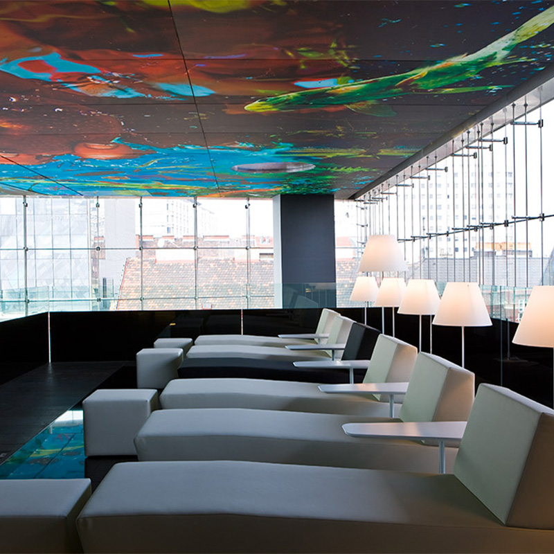 A row of grey loungers beneath a beautiful colourful mural on the ceiling