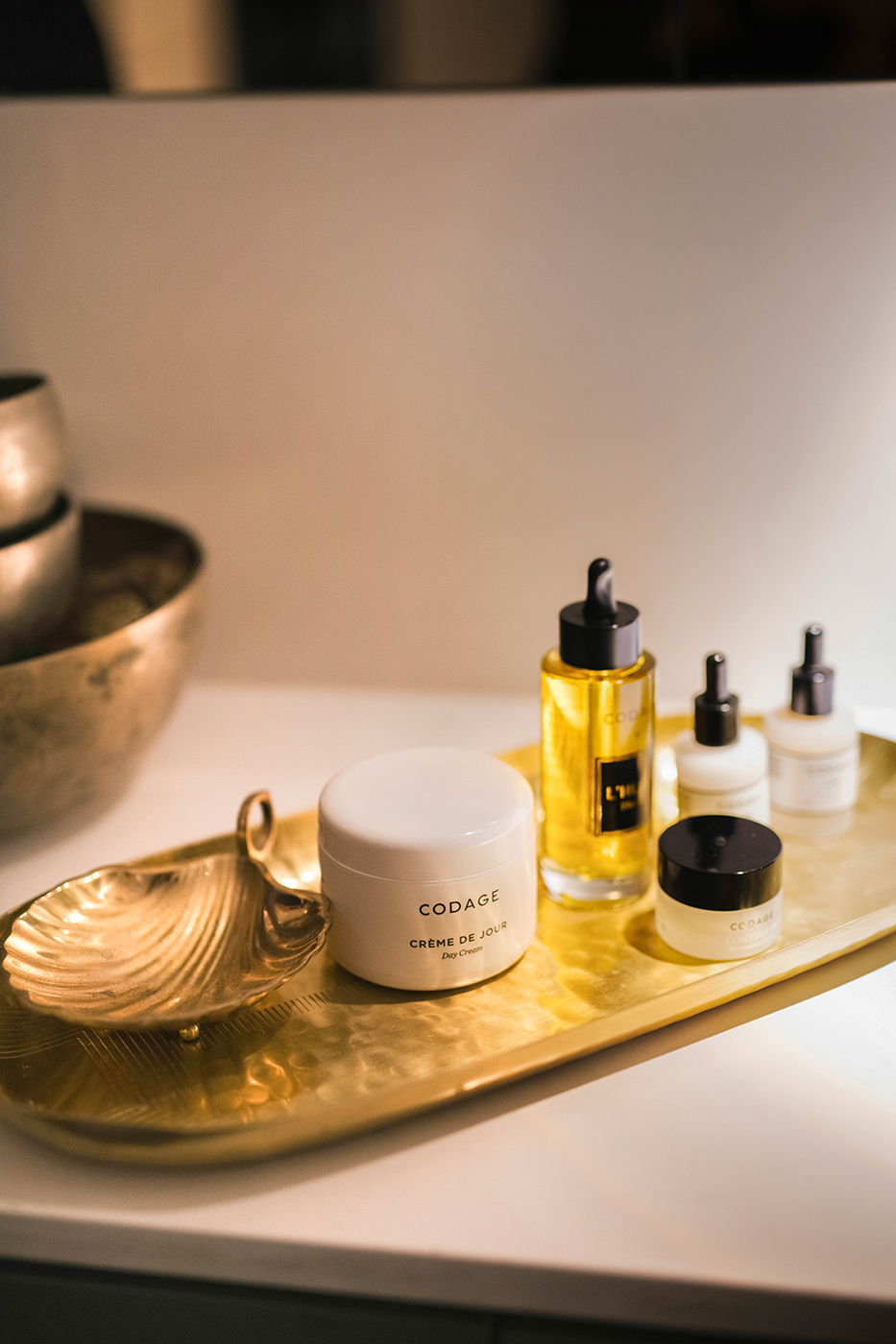 Alt text: Skincare products on a golden tray, including a cream jar and dropper bottles, exude a luxurious, serene atmosphere with warm lighting.