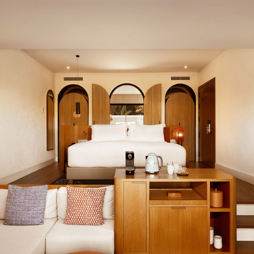 http://A%20hotel%20room%20featuring%20a%20bed,%20a%20couch,%20and%20a%20coffee%20table,%20creating%20a%20cozy%20and%20inviting%20atmosphere.
