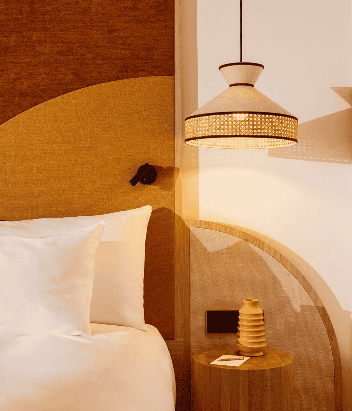 A neatly made bed with white sheets and a lamp placed on the nightstand beside it.