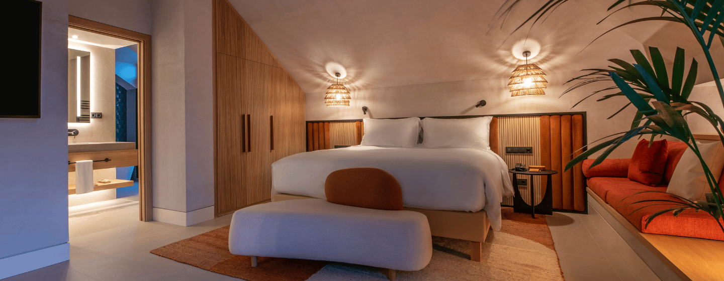 A hotel room featuring a bed, a television mounted on the wall, and a comfortable couch.