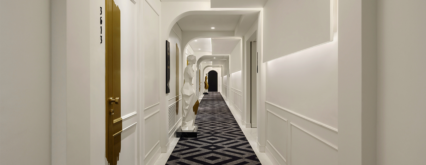 A long white hallway with patterned flooring and statues lining the hallway