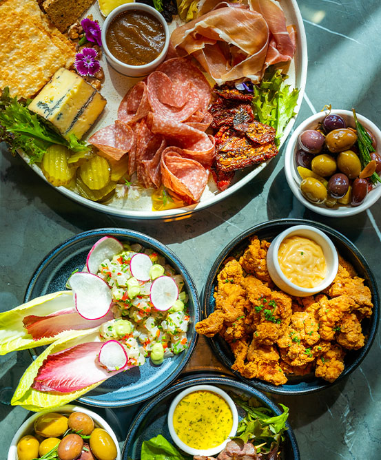 Multiple dish plate filled with meats, cheeses, vegetables and dips