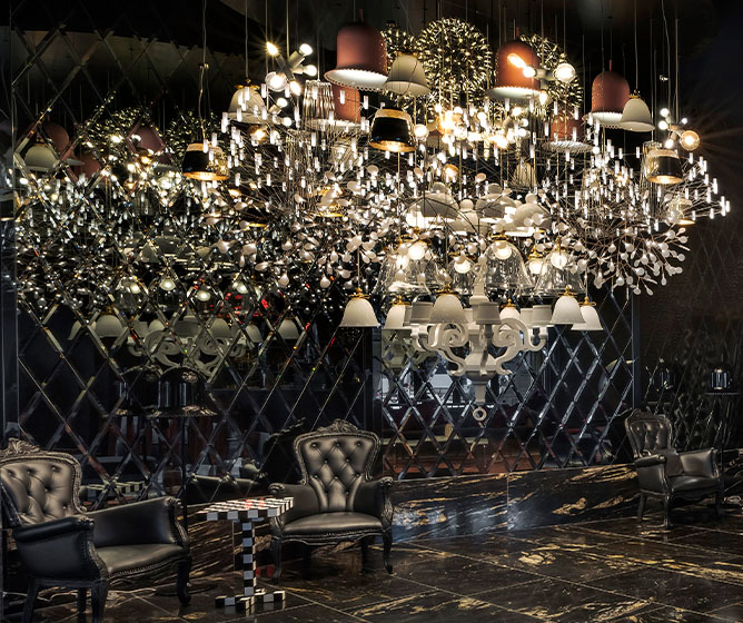 A beautiful large chandelier hanging in a dark room above large black armchairs