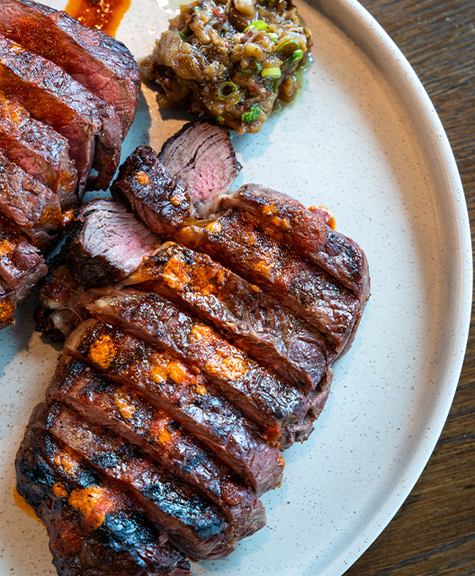 http://Two%20steaks%20cut%20up%20on%20a%20plate%20with%20a%20garnish%20on%20the%20side%20on%20a%20white%20ceramic%20plate