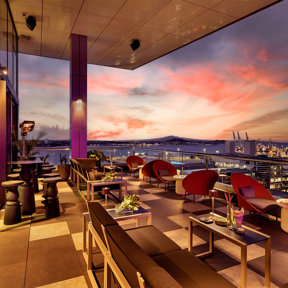 A dining area on a large balcony looking over the beautiful Auckland skyline at sunset.