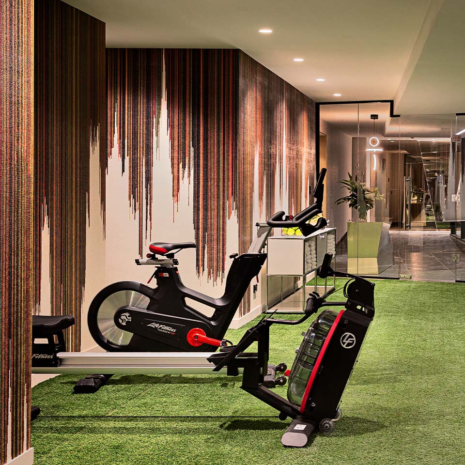 A rowing machine and spin bike in a large gym with grass coloured flooring