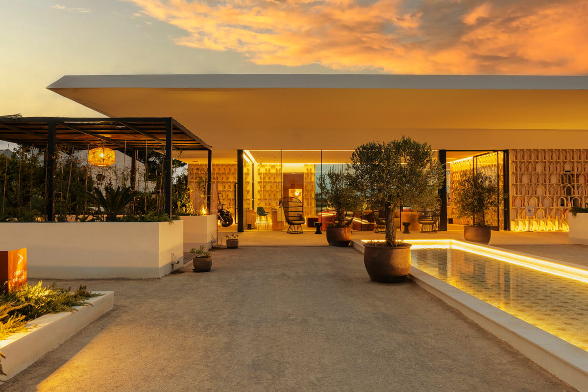 Reception building from the outside with a pavillion and a water basin while the sun sets