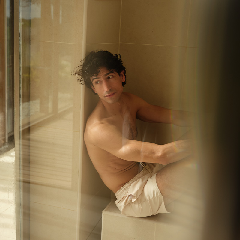 A man relaxing in a wooden panelled sauna looking out of a window