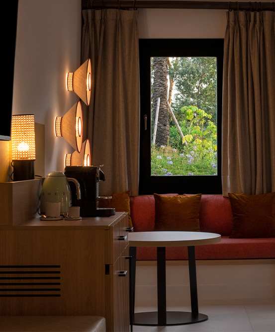 A cabinet with refreshements and a small couch by the window looking out into nature