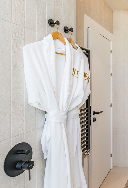 http://A%20His%20and%20Hers%20white%20robe%20hanging%20up%20in%20a%20white%20bathroom
