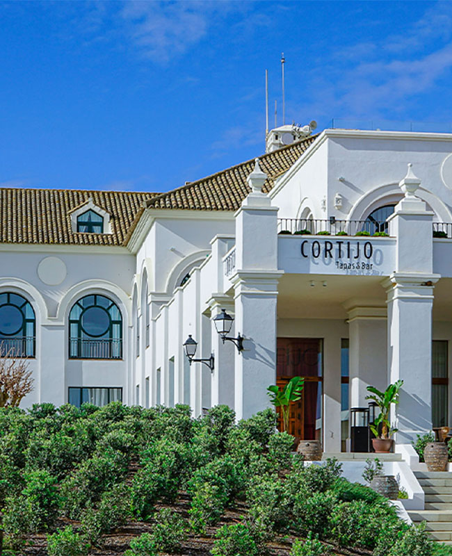 Exterior of the white Cortijo Tapas and Bar building under a clear blue sky