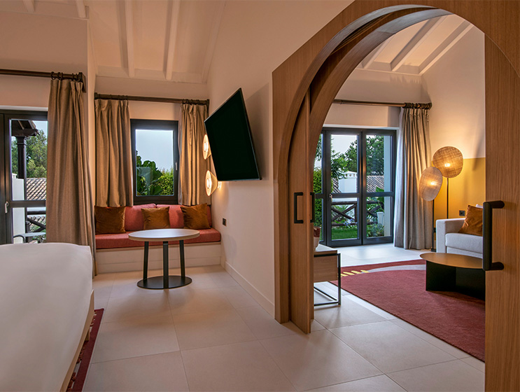 A large open arch door separate a bedroom and lounge area