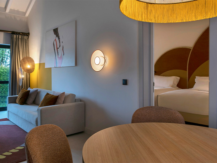 A room showcasing a couch and a table, a large door leads to the bedroom, designed for both rest and socializing.